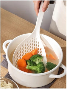 Detail showing a large white skimmer straining carrots and broccoli from a cooking pot
