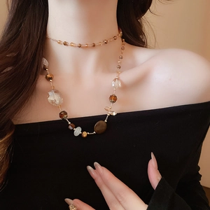 Dettaglio della collana a strati con perle di ambra e marmo indossata da una modella