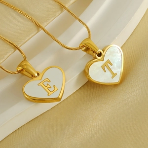 Detailed close-up of golden heart necklaces with letter E and T on white pedestals