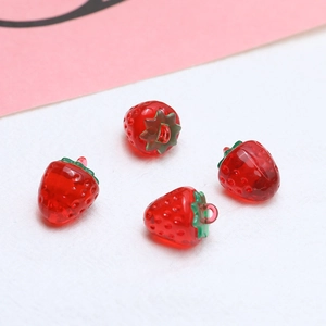 Macro detail of red resin strawberry charms with green leaves and metal rings for jewelry