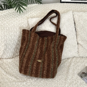 Detail of soft brown teddy fleece tote bag with green stripes and gold logo plate