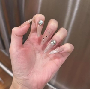 Elegant stiletto press-on nails with nude pink base, black polka dots and crystal accents