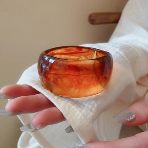 Minimalist irregular wave resin bangle featuring amber cloud patterns worn by a model