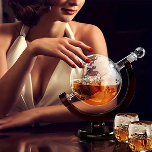 Close-up of world map etched globe decanter with dark wood stand and crystal glasses