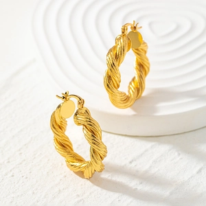 Minimalist twisted rope hoop earrings in 18k gold plated finish on white marble stand