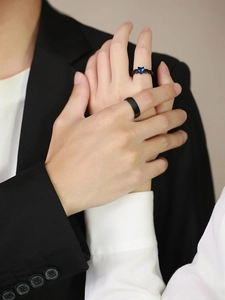 Close-up of black stainless steel couple rings featuring a blue heart-shaped gemstone
