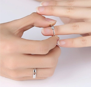 Close-up of silver couples rings with heart-shaped stone and hollow-out heart design