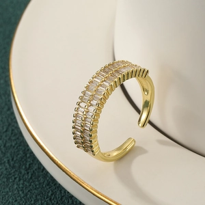 Adjustable gold double-row ring with rectangular zircons on a white ceramic dish
