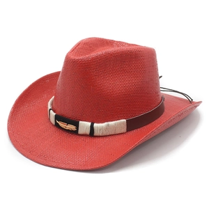 Red woven cowboy hat with leather band and gold feather charm on white background