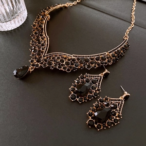 Détail de strass noirs en goutte sur collier doré et boucles d'oreilles vintage