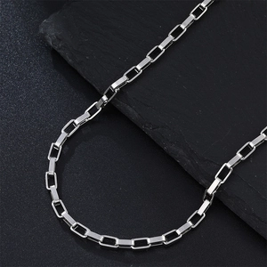 Detailed close-up of a silver rectangular link chain on a textured slate background