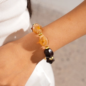 Close-up of amber and dark brown beaded bracelet with golden spacers on a wrist