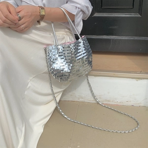 Close-up of sparkling silver sequins and metal chain strap on a large canvas tote bag