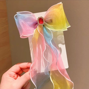 Detail of colorful gradient bow hairclip with red rhinestone and sheer fabric texture