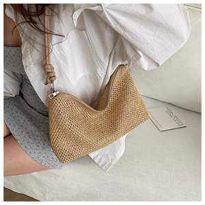 Detail of hand-woven straw tote bag with knot shoulder strap and zipper closure