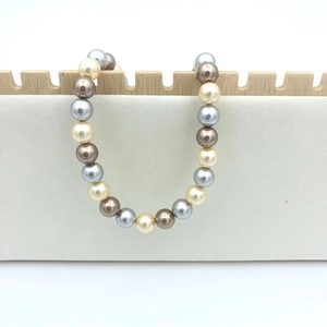 Elegant multi-color gradient pearl necklace with cream and bronze tones on a white stand