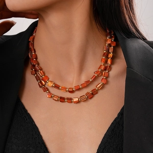 Close-up of vibrant orange layered shell bead necklace worn on model for summer styling