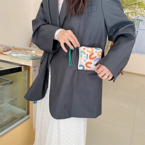 Detailed view of a small quilted floral coin purse being tucked into a blazer pocket