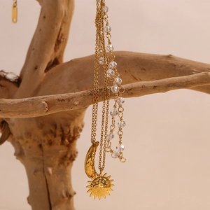 Detail of 18K gold-plated star and moon pendant on a layered beaded chain necklace