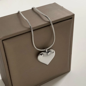 Polished silver heart pendant necklace with square snake chain on jewelry box
