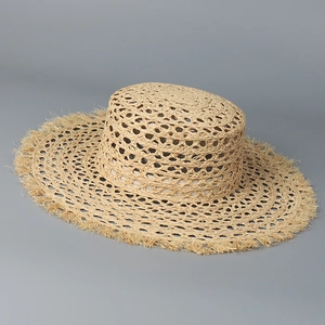 Detailed view of hollow woven raffia straw hat with unique fringed raw edges on the brim