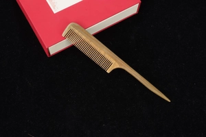 Macro detail of fine-tooth green sandalwood comb with rounded handle and red gift box