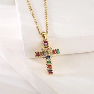 Detailed macro view of gold cross pendant with colorful zircon stones on white texture