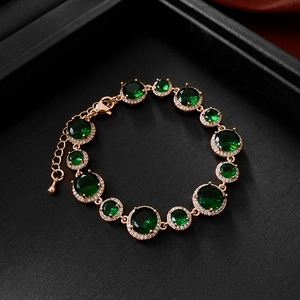 Detail of vintage gold-plated bracelet with emerald-style zircons on black tray