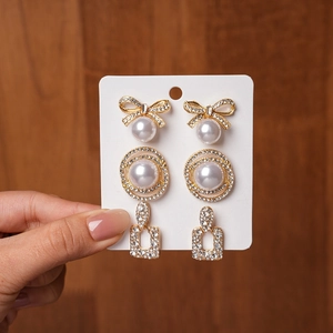 Detailed set of three earrings featuring bow pearls, rings, and geometric rhinestones