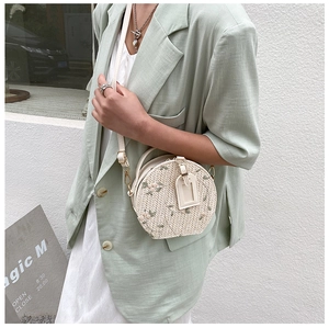 Detail of round straw bag with flower embroidery and adjustable white leather strap