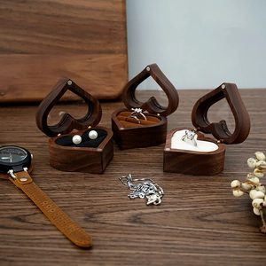 Three heart-shaped walnut ring boxes with white, black, and brown velvet linings