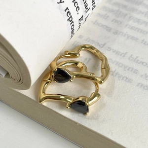 Close-up of S925 silver gold earrings with black heart stones and fluid metal frame