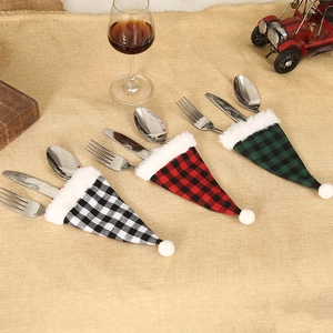 Detail of plaid Christmas hat cutlery holders in red, green, and grey on a festive table