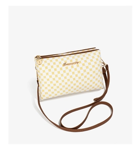 Detailed view of dual golden zippers and geometric print on white crossbody bag