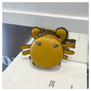 Detail of yellow crab leather coin purse featuring metal rivet eyes on a book