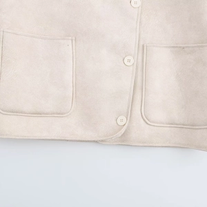 Detail of beige faux suede jacket showing pocket structure and button texture