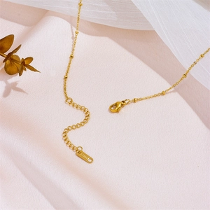 Elegant gold stainless steel necklace with cross tassel and lobster clasp on soft fabric