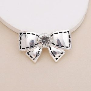 Close-up of silver metal bow with a central rhinestone and black stitching details
