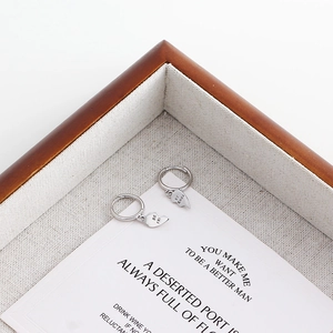 Macro shot of silver heart earrings engraved with Best Friends on a wooden tray