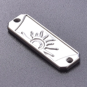 Macro detail of a silver rectangular sun pendant with two holes for DIY jewelry