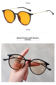 Detail view of retro round sunglasses with black frames and brown lenses with gold temples
