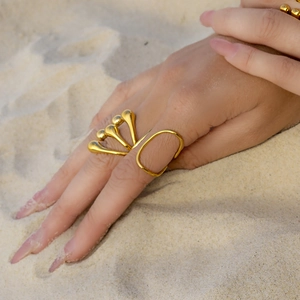 Irregular liquid style gold flower ring for women worn on a sandy beach setting