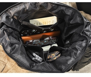 Interior view of black quilted tote bag featuring one zipper pocket and two open compartments