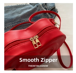 Close-up of heart-shaped red leather bag with embossed patterns and gold zippers