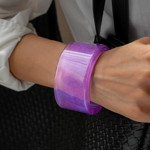 Close-up of wide purple resin bangle with glitter texture worn on a wrist