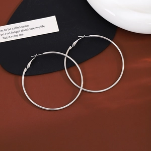 Minimalist silver hoop earrings on a vintage leather pad with artistic white ceramic decor