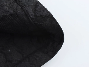 Macro detail of the black jacquard fabric texture on the long trench coat sleeve
