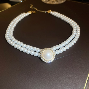 Detail of double-layer pearl necklace with a gold pendant and sparkling zircon stones