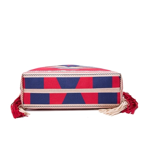 Close-up of bohemian woven shoulder bag featuring geometric patterns and long red fringes