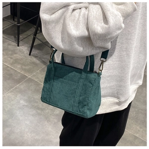 Detail of dark green corduroy Boston bag shown on a model for a crossbody styling look